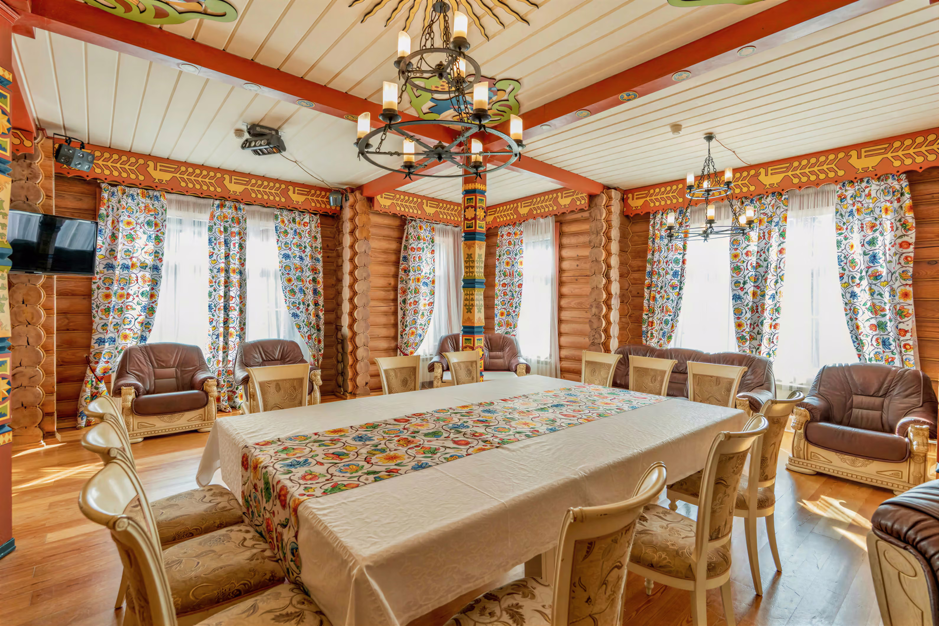 Столовая с длинным столом, расписными балками и деревянными стенами
